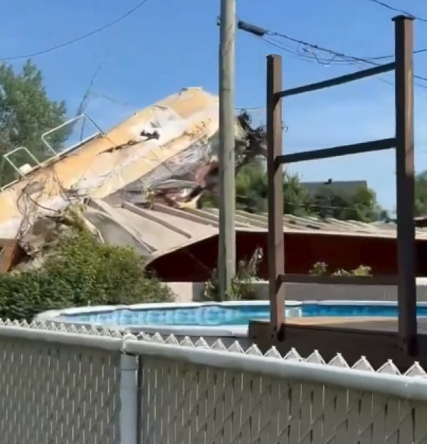 A train car derailed into a residential backyard with a swimming pool.