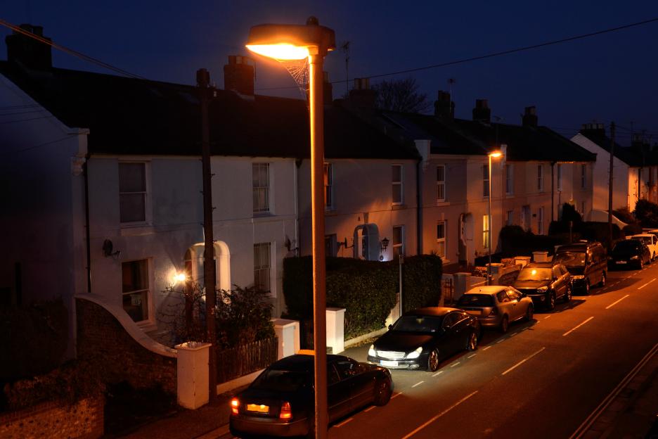 A car arriving in front of a row of terraced cottages at dusk.
