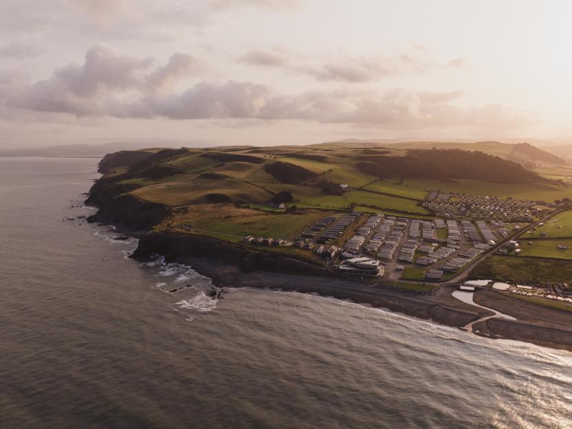 Aerial view of Allens Caravans park by the sea at sunset.