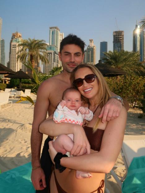 A family with a baby on a beach in front of a city skyline.