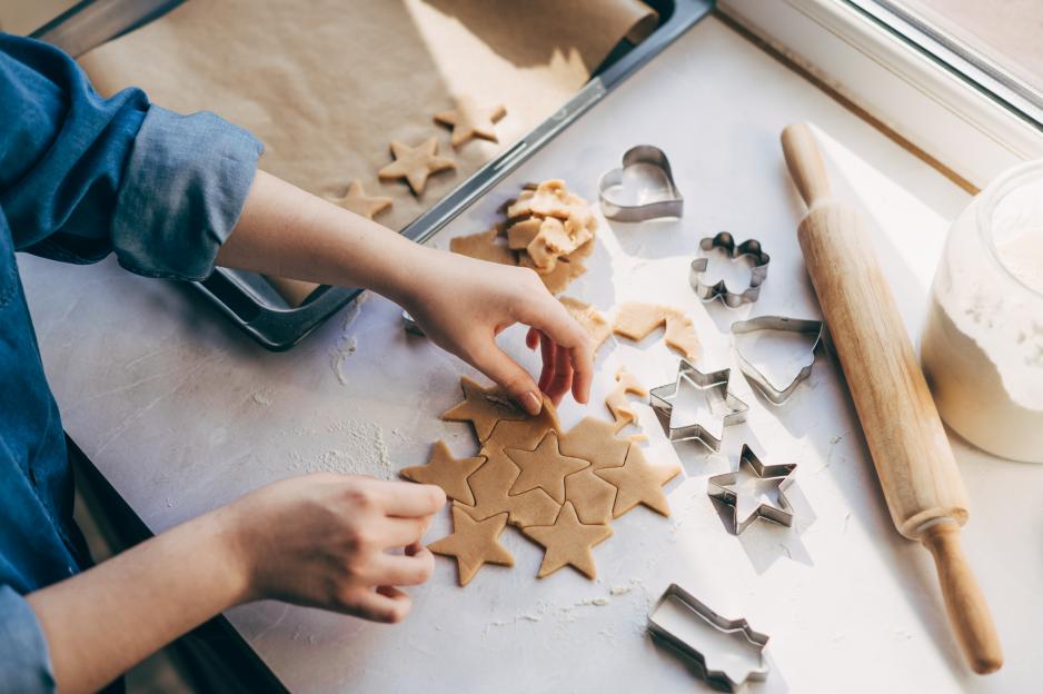 Person cutting out star-shaped cookies from dough.