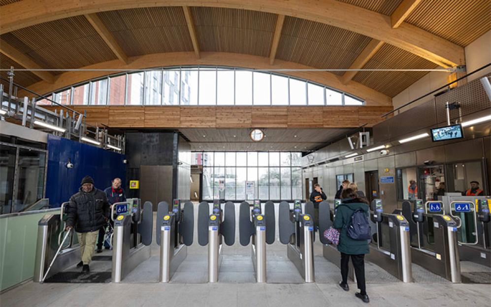 Commuters at a new Crossrail station with a large wooden arched ceiling.