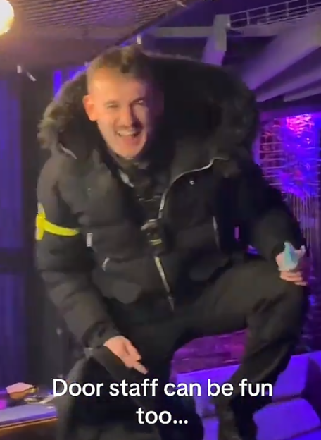 A man wearing a black parka with a fur-lined hood and a yellow armband laughs as he crouches down, with the text "Door staff can be fun too..." below him.