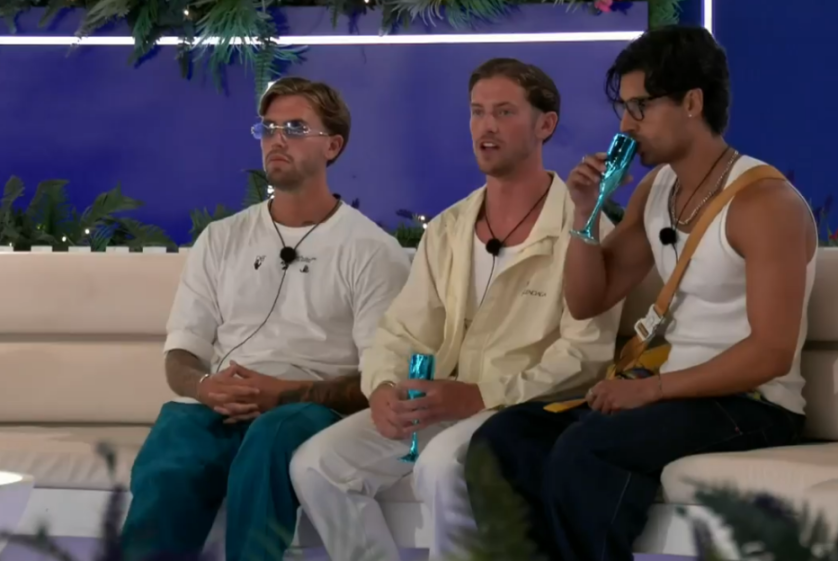 Three men sitting, two holding blue glasses, one drinking from his glass.
