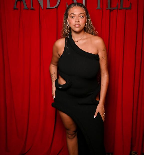 Mahalia in a black dress against a red backdrop for British GQ and Christian Louboutin.