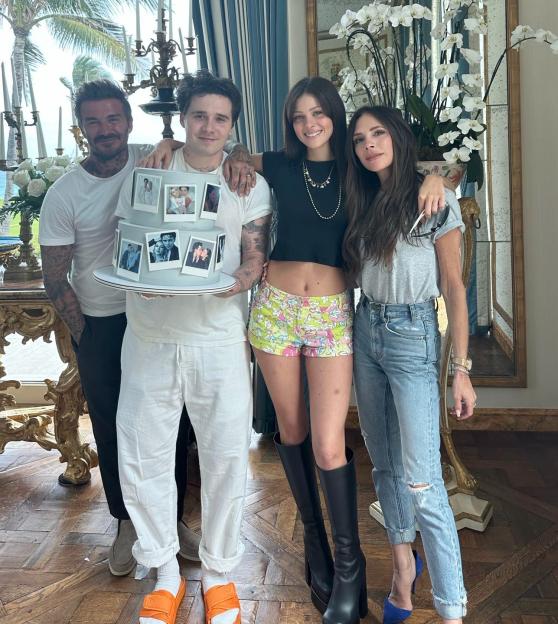 David Beckham, Victoria Beckham, Brooklyn Beckham, and Nicola Peltz Beckham celebrate their first wedding anniversary with a cake featuring photos.