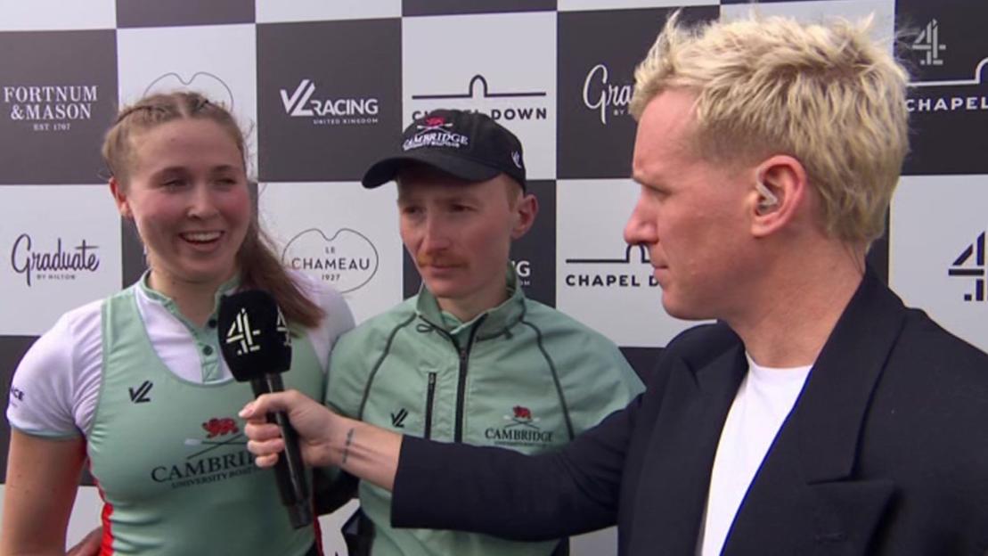 A female and male Cambridge University rowers are interviewed by a male reporter with blond hair.