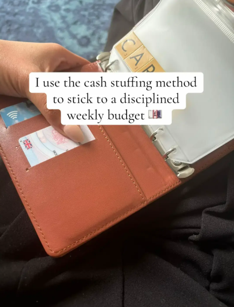 A person holding a brown wallet with a UK driver's license inside and a clear plastic pouch with "CAP" written on it.