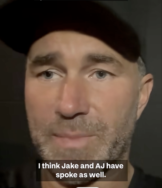 A man in a black cap and t-shirt, with a light beard, looks slightly to the right, with the subtitle "I think Jake and AJ have spoke as well."