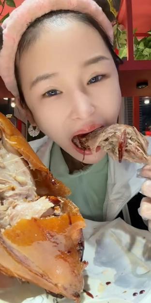 A young woman eating a whole cooked chicken.