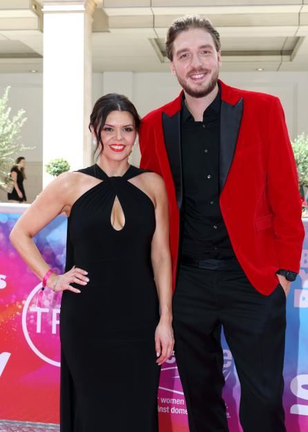 Roxanne Hoyle, in a black dress, and Mark Hoyle, in a red jacket, smiling at the TRIC Awards.