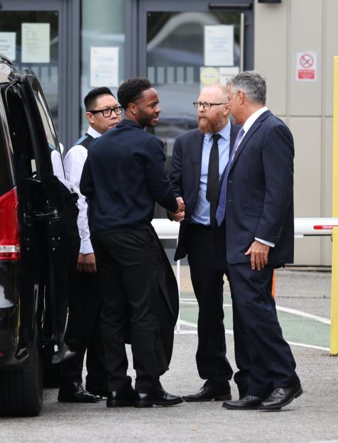 Raheem Sterling shaking hands with a man in a suit.