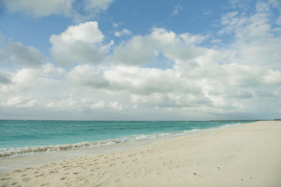 White sand beach with turquoise water and scattered clouds in South Caicos.