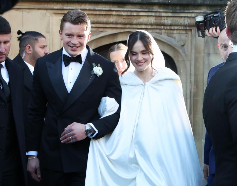 Adam Peaty in a tuxedo and Holly Ramsay in a white gown at their wedding.