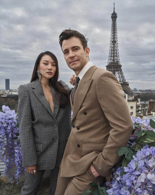 Michelle Yeoh and an unknown man pose on a rooftop with the Eiffel Tower in the background.