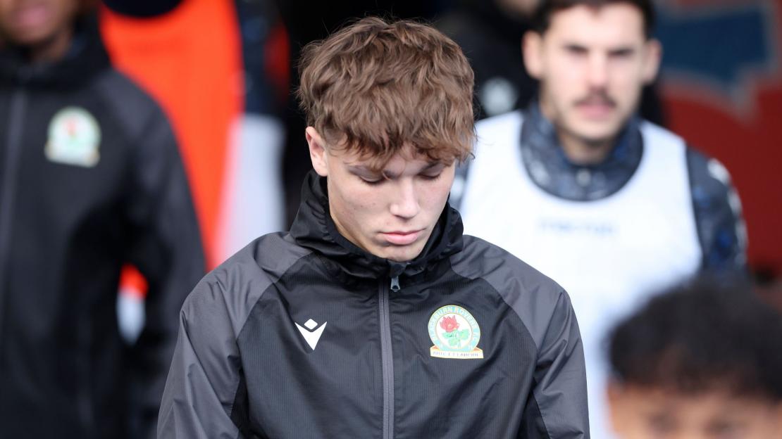 A Blackburn Rovers player in a black and grey track jacket with the team crest.