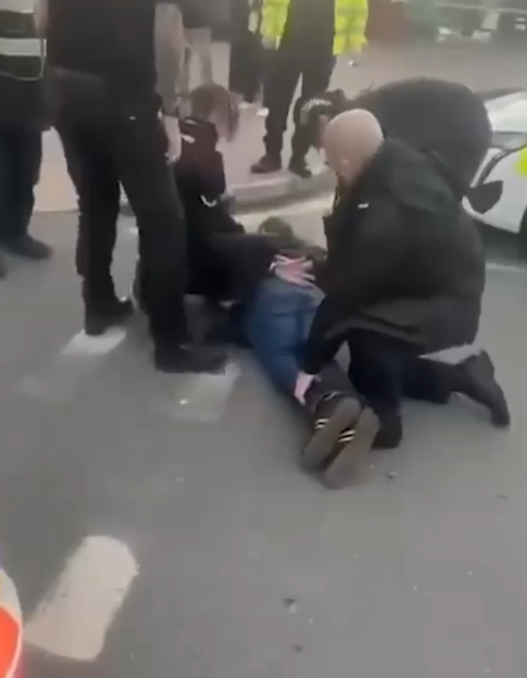 Police officers detaining a person on the ground.