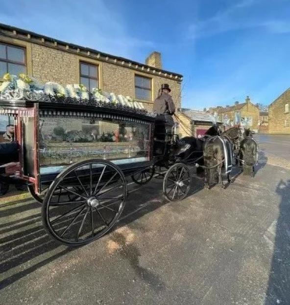 Horse-drawn hearse with a driver in a top hat.