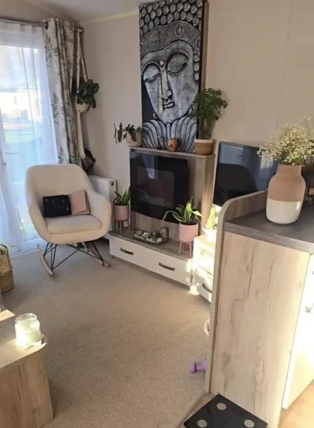 A caravan interior with a neutral color palette, featuring a Buddha-themed wall decoration and text overlay "VERSUS MY FLAT".