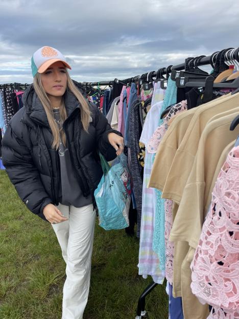 A young woman holding a blue IKEA bag at a car boot sale.