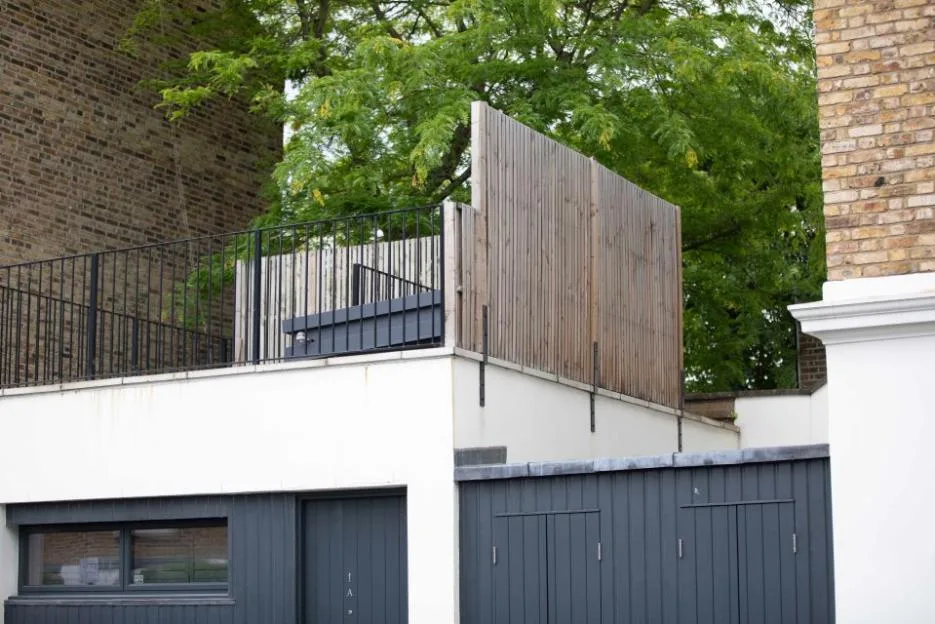 A roof terrace enclosed with wooden fencing and metal railings on a building in Notting Hill.