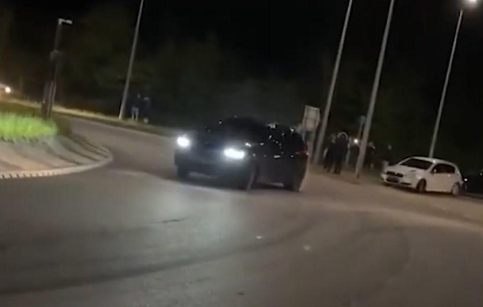 A black BMW X3M Competition drifting around a roundabout at night.