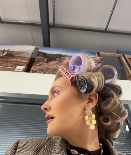 Woman with hair in curlers and an earring looking up and to the right.