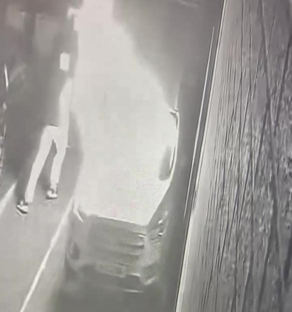 CCTV footage shows two figures near a car, one of which appears to be on fire.