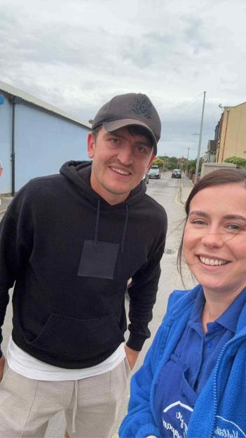 Harry Maguire posing for a selfie with a woman in a blue jacket.