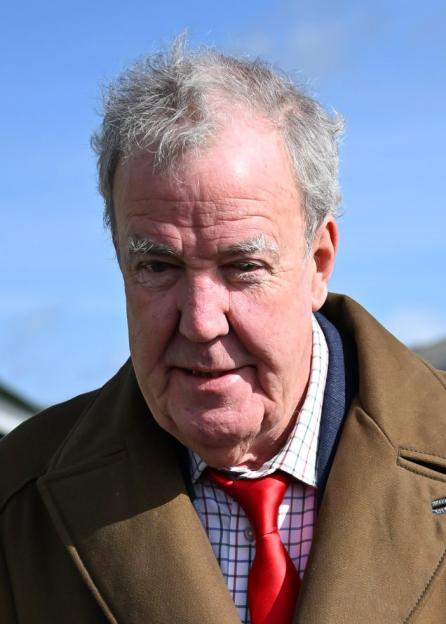 Jeremy Clarkson wearing a brown coat and red tie at Cheltenham Festival.
