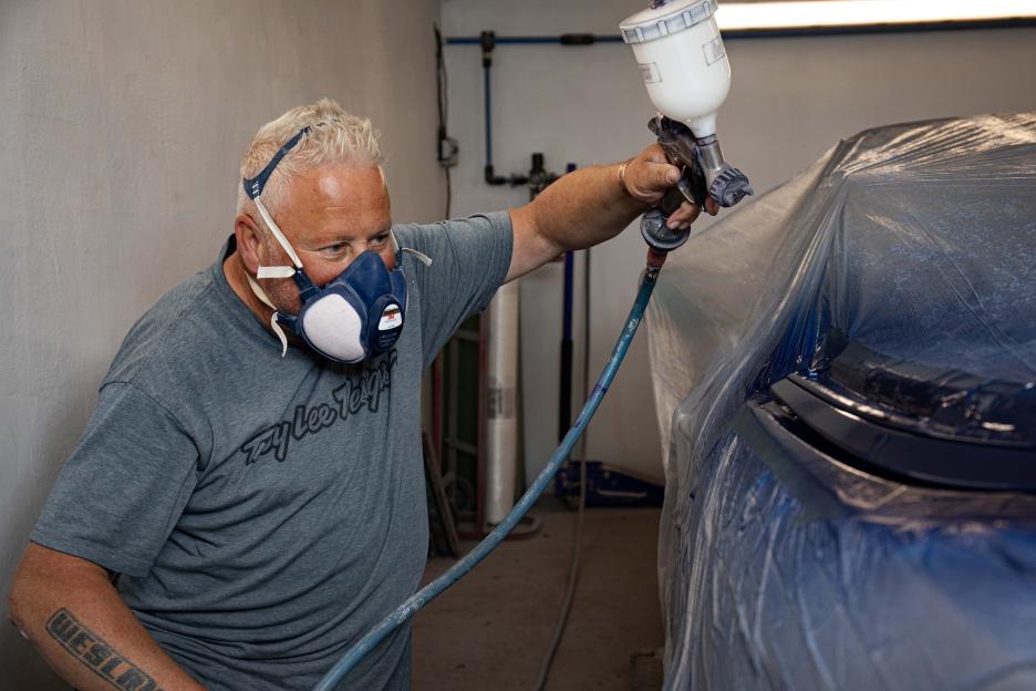 Martyn Smith painting an orange breastplate for Kim Kardashian's Met Gala outfit.