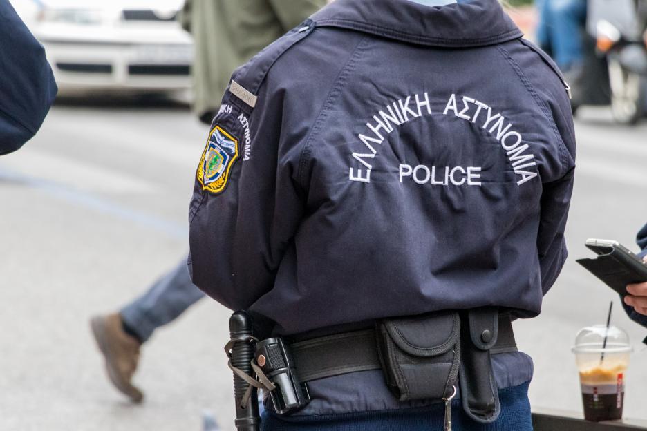 Astynomia police sign-logo on the back of a police uniform standing outdoors.