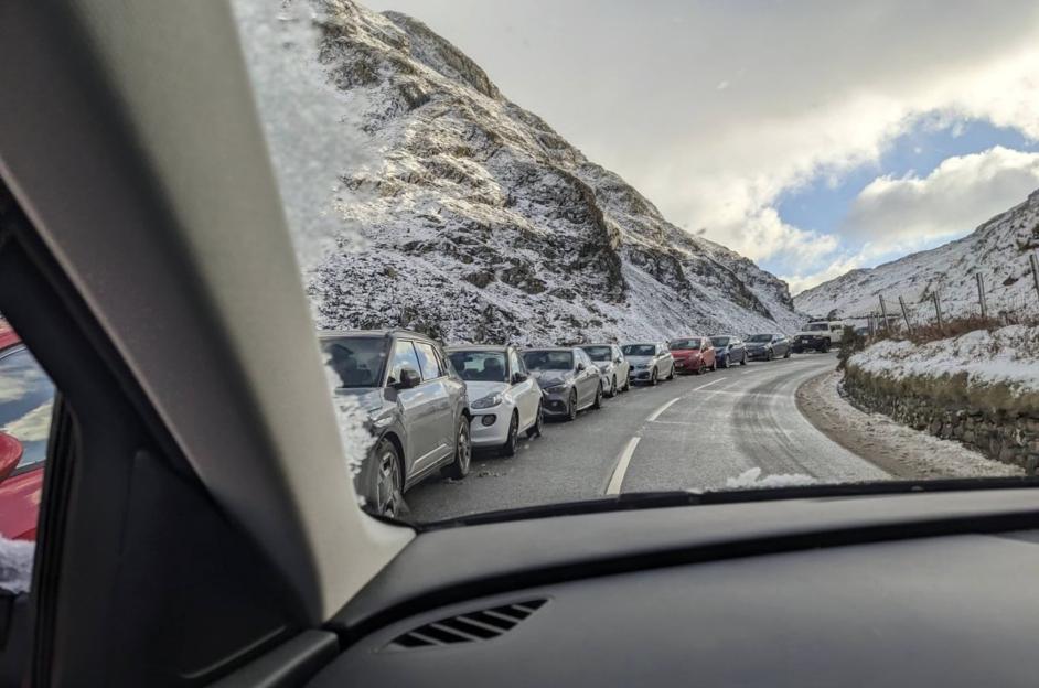 Cars parked along a snow-covered mountain road.