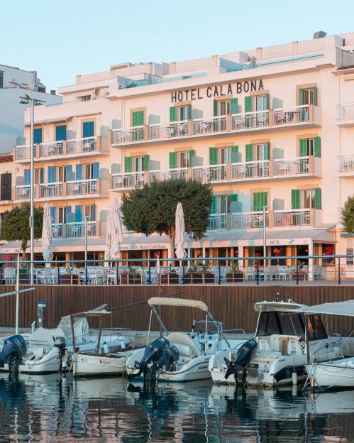 Hotel Cala Bona on Mallorca, seen from the water, with boats docked in the foreground.