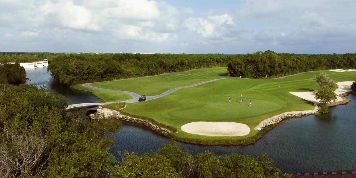 An aerial view of the Fairmont Mayakoba golf course with a river, lush trees, and golfers.