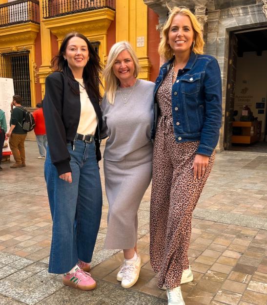 Jasmine Harman (right) posing with two other women in a city street.
