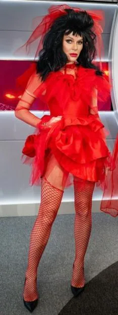 Amanda Holden and Ashley Roberts in Halloween costumes, with Holden dressed in a red tulle dress and veil, and Roberts painted blue with orange hair, wearing a sash that reads "Miss Receptionist."