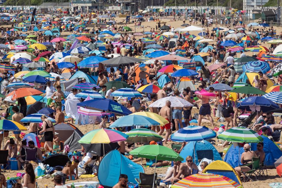 Crowded beach filled with colorful umbrellas and sunbathers.