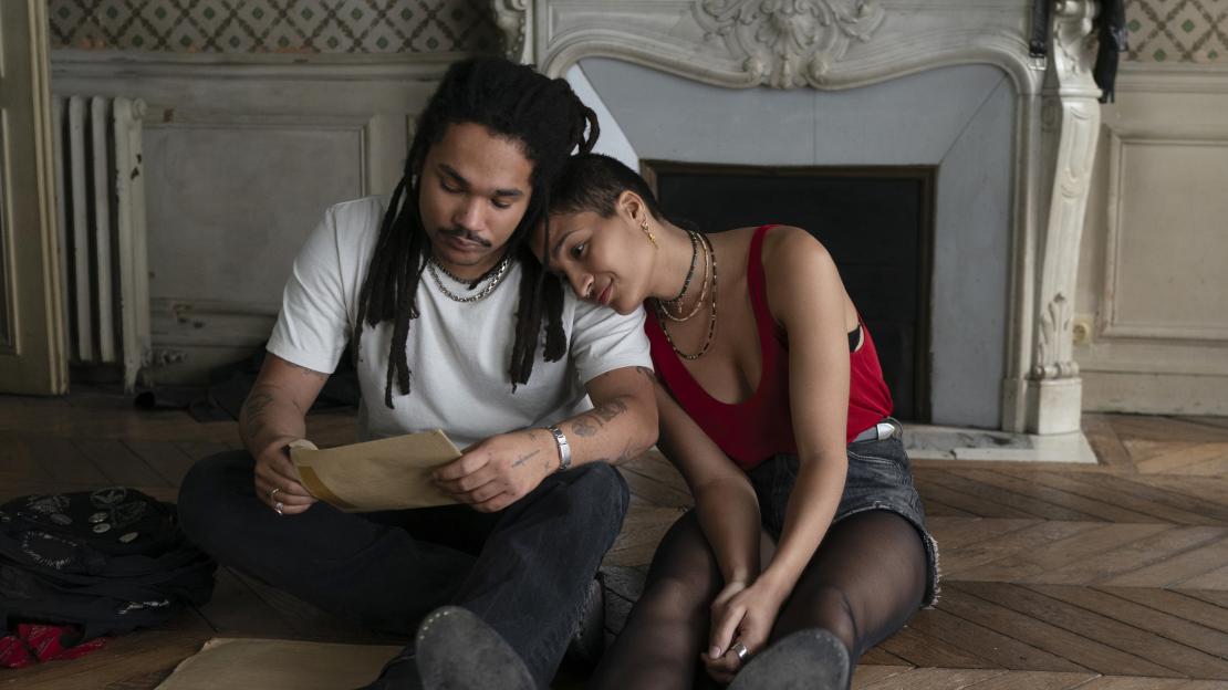 Luka Sabbat as Billy and Indya Moore as Skye sitting on the floor together.