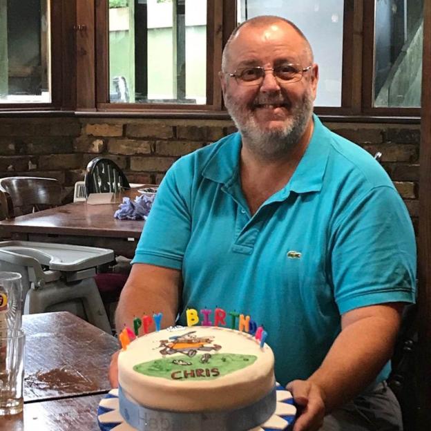 Christopher Bottoms smiling and holding a birthday cake.