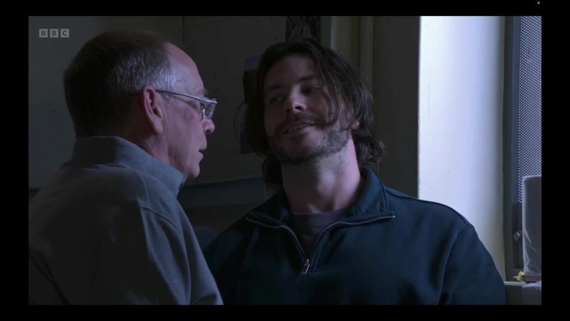 Two men talking, one with glasses, the other with a beard.