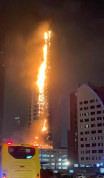 The Burj Al Arab on fire at night with flames and sparks extending up the side of the building.