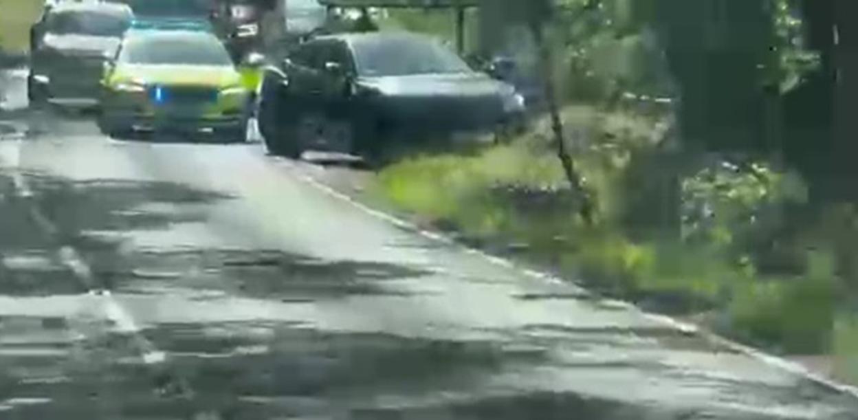 Vehicles on a road with a police car in the distance.