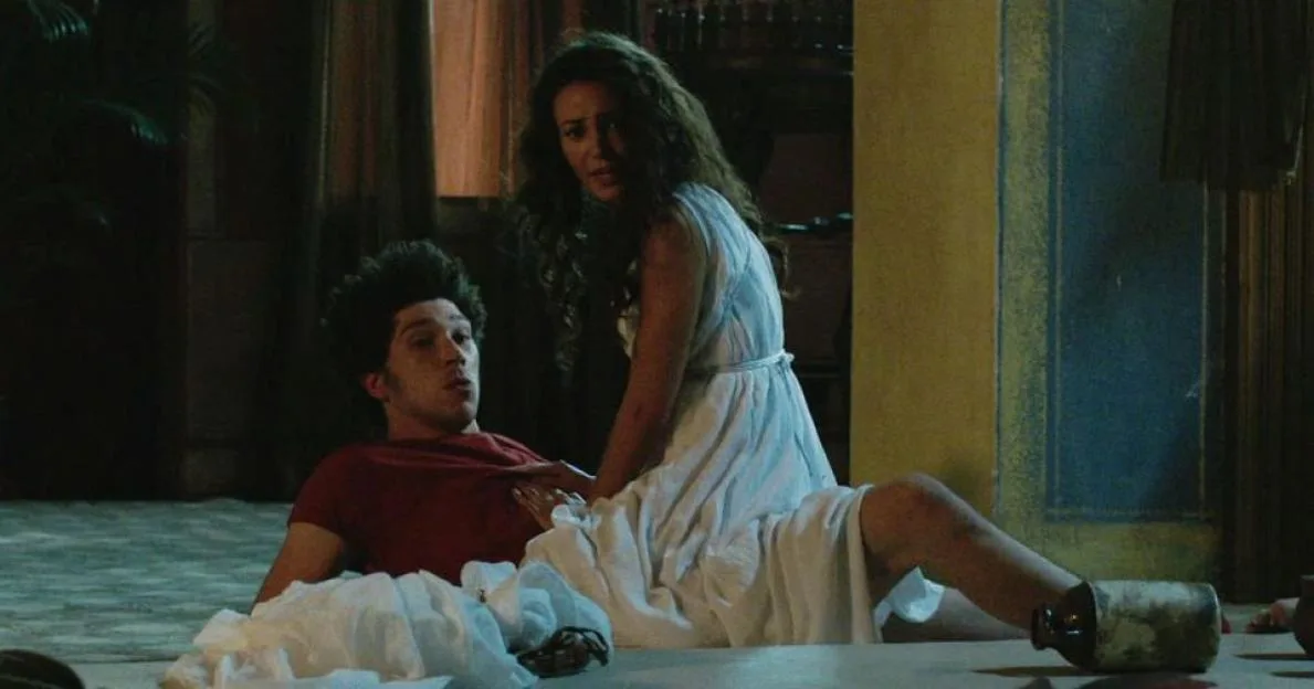 Michelle Keegan in a white dress kneeling over a man in a red shirt.