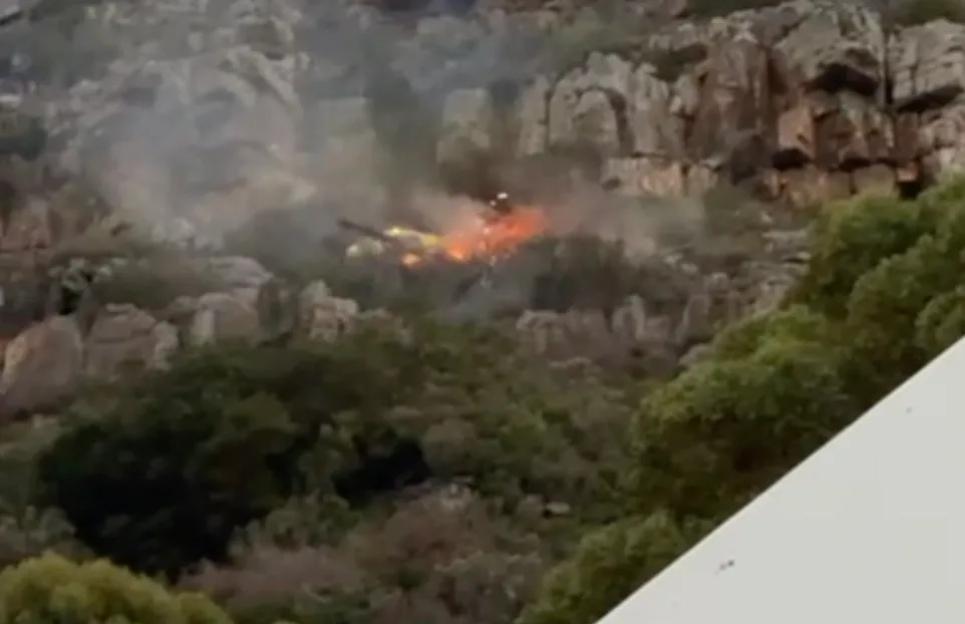 JPHBCHOP2 to 9 shows a Working On Fire Bell Huey chopper approaching the Vlakkenberg Mountain at the rear of Table Mountain in Cape Town with a 1000 litre bucket of water hanging below it to drop on a small fire as it mops up after an earlier larger