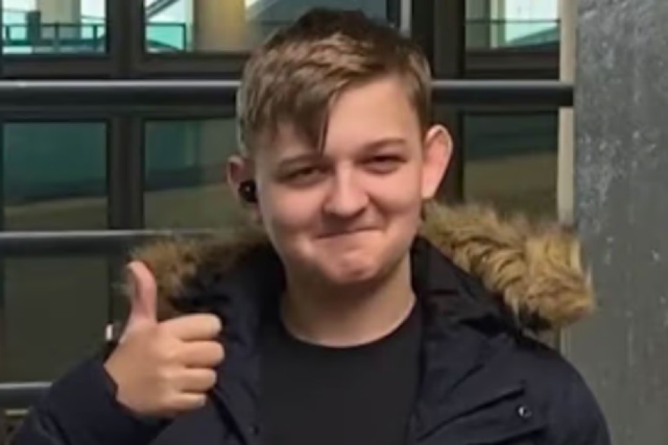 George Herd, an 18-year-old in a dark blue jacket with a fur-lined hood, giving a thumbs up.