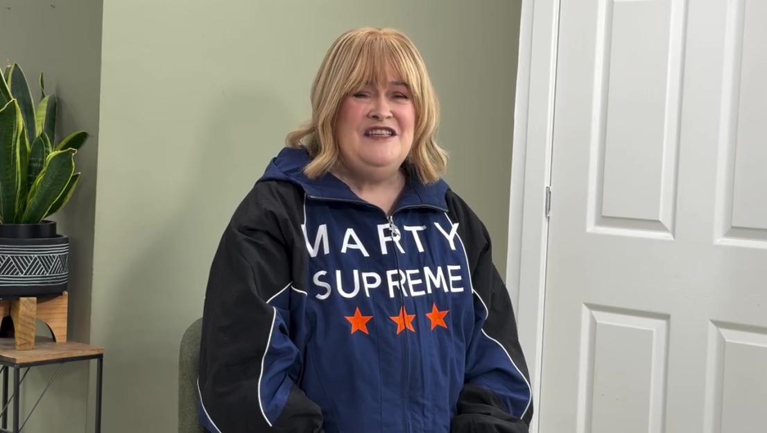Susan Boyle in a navy blue and black "Marty Supreme" jacket with three orange stars.