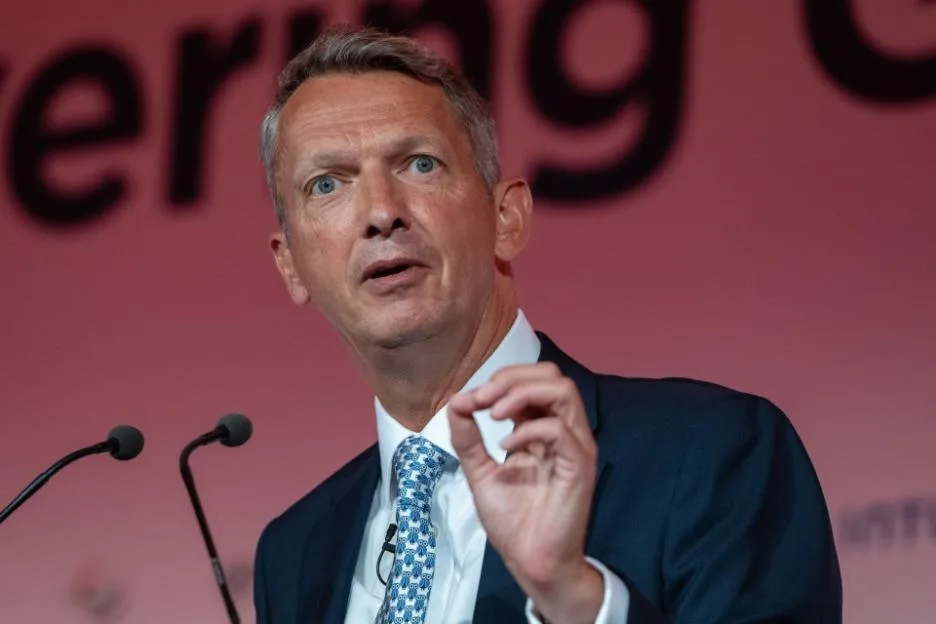 A man in a suit and blue patterned tie speaks at a podium during the British Chambers of Commerce Global Annual Conference.