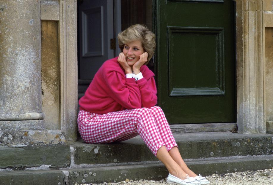 Diana, Princess of Wales, seated on steps outside Highgrove House in pink gingham trousers and a matching pink jumper.