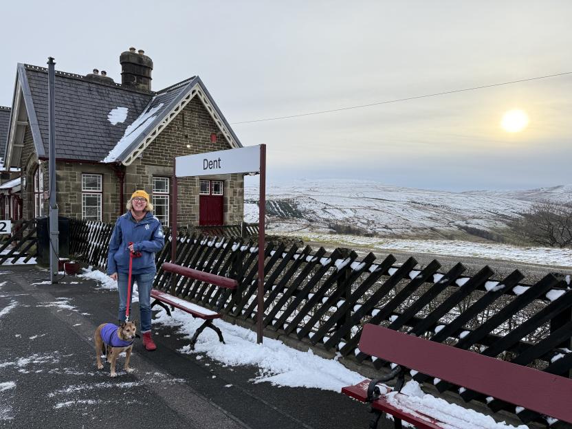 Tracey Davies with her dog on a snowy platform at Dent station in Yorkshire.